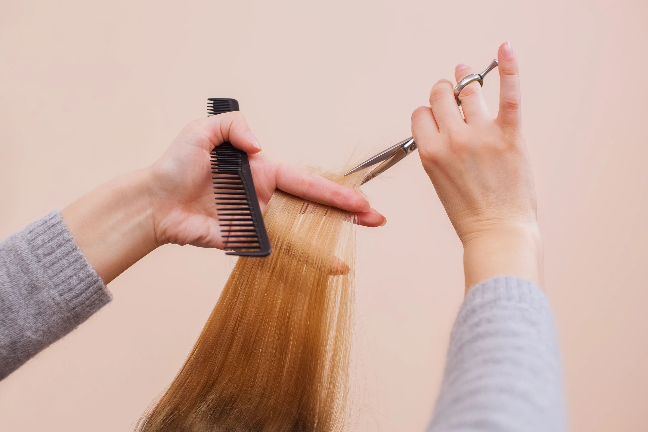 Hands styling hair with scissors and comb